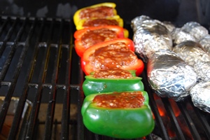 De gevulde paprika's met gehakt en een topping van barbecuesaus indirect geplaatst op de barbecue