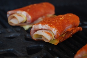 De rollade van varkensfilet met ham, kaas en pesto geserveerd met sugar snaps, indirect op de barbecue opwarmen