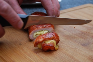 De Rollade van varkensfilet met ham, kaas en pesto aansnijden in gelijkmatige plakjes